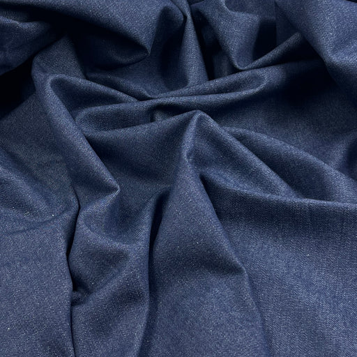 A close-up of draped navy blue fabric with a fine textured weave, showing soft folds and shadows.