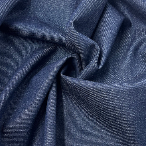 Closeup of heavyweight indigo denim pulled into a swirl to show off the texture and drape. 