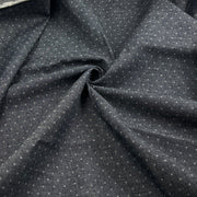 Dark charcoal gray fabric with a small white geometric dot pattern, draped in a central swirl to show texture and drape.