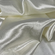 A close-up image of crepeback satin fabric in ivory color, showing its shiny satin face and textured reverse.