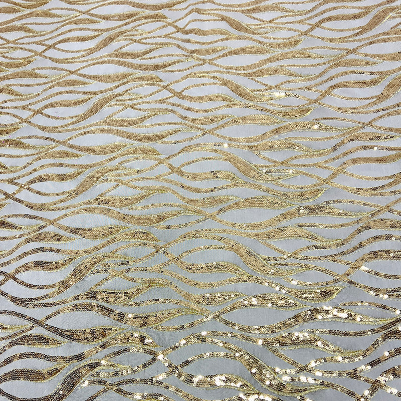 Gold sequined fabric with a wavy, flowing pattern on a light gray background.