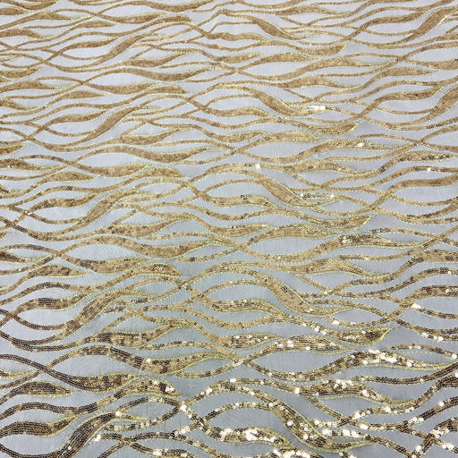 Gold sequined fabric with a wavy, flowing pattern on a light gray background.