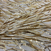 White sequin fabric with a wavy gold sequin pattern draped in soft folds.