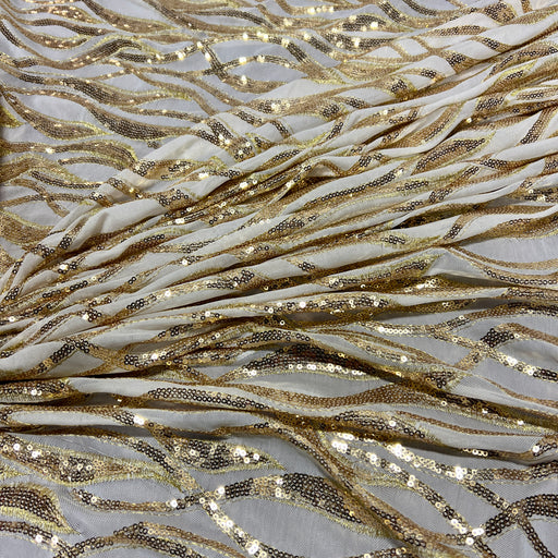 White sequin fabric with a wavy gold sequin pattern draped in soft folds.