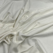 A close-up of draped off-white or cream-colored fabric with soft folds and a smooth texture.