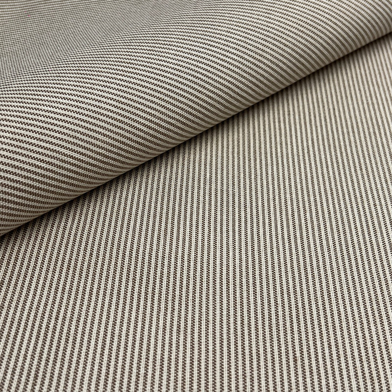 A close-up of woven fabric with a fine striped pattern in beige and brown, shown with one corner folded over to reveal the texture.