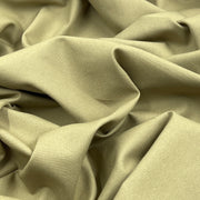 A close-up of draped khaki fabric with soft folds and a smooth woven texture.