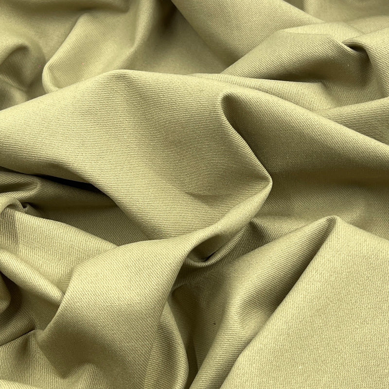 A close-up of draped khaki fabric with soft folds and a smooth woven texture.