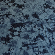 A close-up of a blue and navy tie-dye fabric with a textured, slightly fuzzy surface showing a starburst pattern.