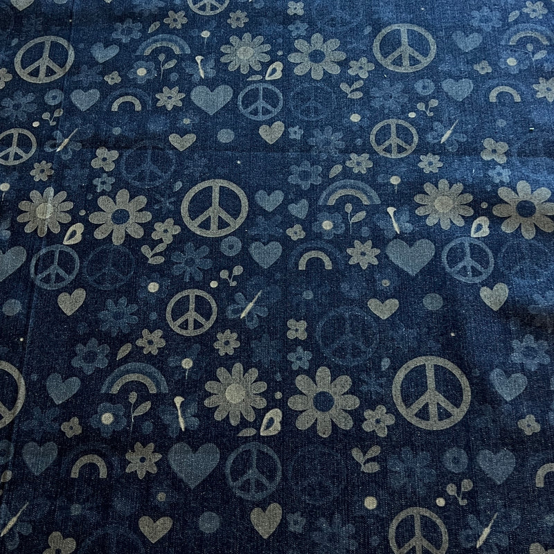 A close-up of a dark navy blue fabric with a repeating pattern of light gray peace signs, hearts, flowers, and small rainbows.