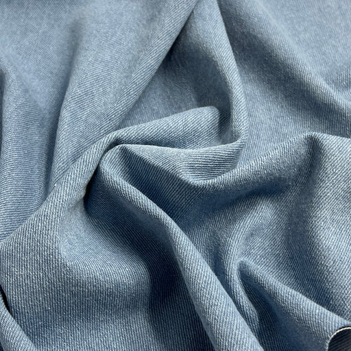 Light blue washed denim bunched into a pile to show off pliable, soft texture