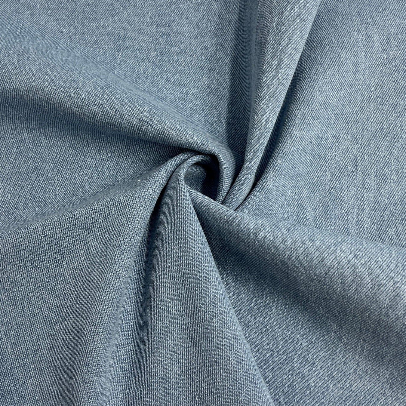 Light blue washed denim folded into a swirl showing off soft movable hand