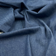 A close-up of draped blue fabric with a fine textured weave, showing soft folds and shadows.