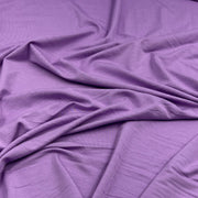 Purple fabric draped in soft folds, showing a smooth texture and matte finish.