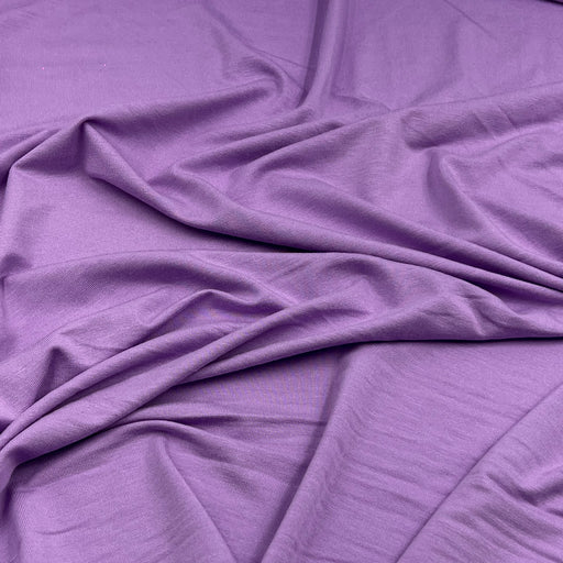 Purple fabric draped in soft folds, showing a smooth texture and matte finish.