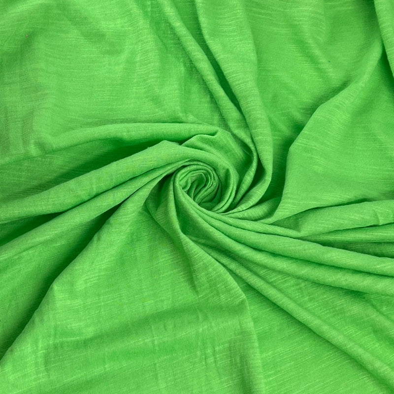 Bright green textured fabric draped in a spiral pattern, showing its woven slub texture.