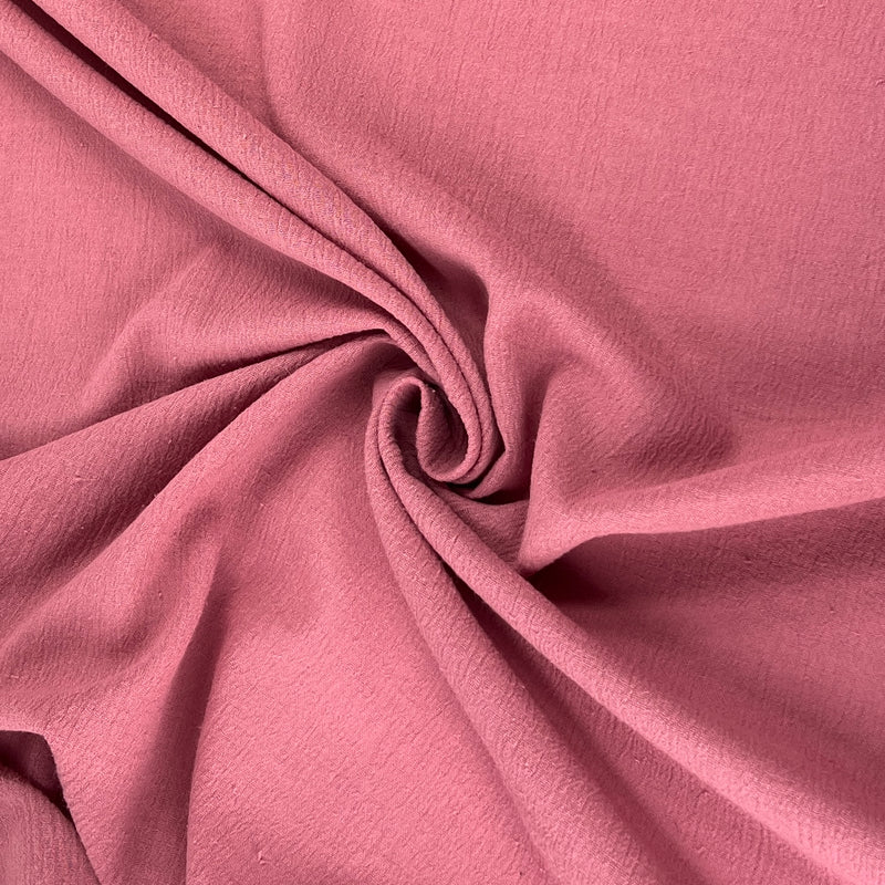 Lightweight 100% cotton bubble gauze in rich mauve pink color pulled into a delicate swirl showing off soft texture and lightweight hand