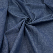 A close-up of draped blue fabric with a subtle heathered texture, arranged in soft folds and a central swirl.