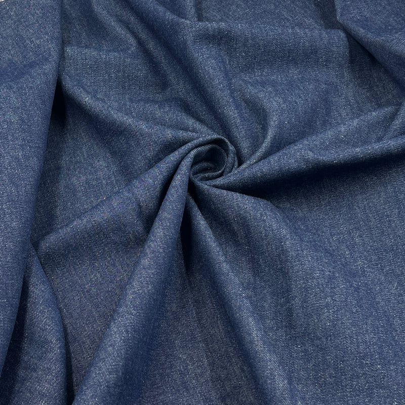 A close-up of draped blue fabric with a subtle heathered texture, arranged in soft folds and a central swirl.