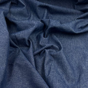 A close-up of draped dark blue fabric with a fine textured weave, showing soft folds and shadows.