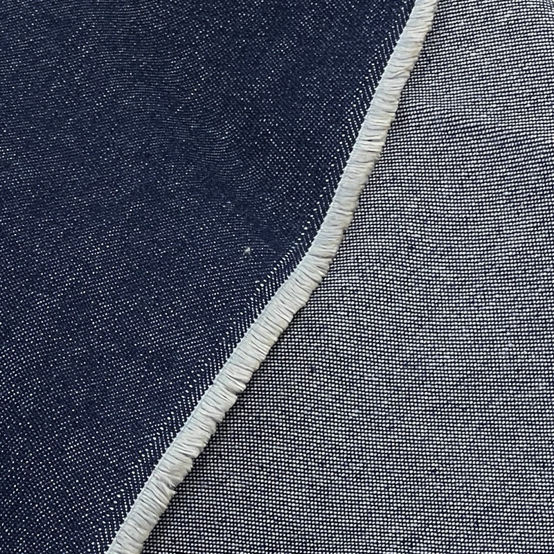 Close-up of a woven textile surface showing a dark indigo blue area on the left and a lighter heather gray-blue area on the right, divided by a frayed white edge.