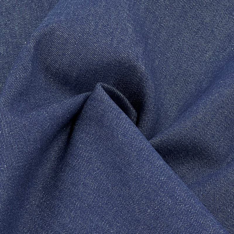 A close-up of dark blue denim fabric with a visible twill weave and soft folds.