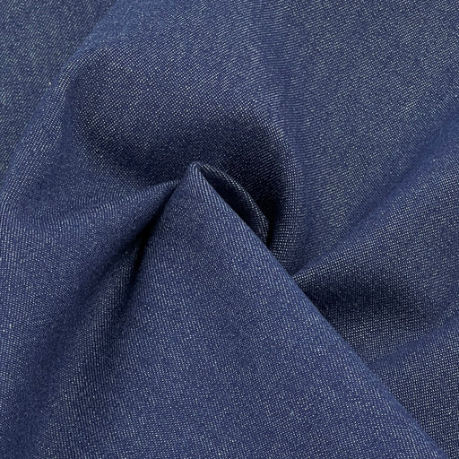 A close-up of dark blue denim fabric with a visible twill weave and soft folds.