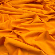 Bright orange fabric draped in soft folds, showing a smooth texture and rich color.