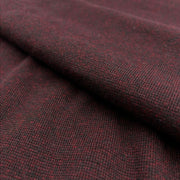 A close-up of textured knit fabric in a dark heathered burgundy red and black colorway, showing the fine woven pattern and soft folds.