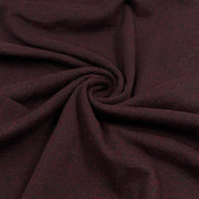 A close-up of dark burgundy fabric with a subtle woven texture, arranged in a spiral drape to show its softness and color.