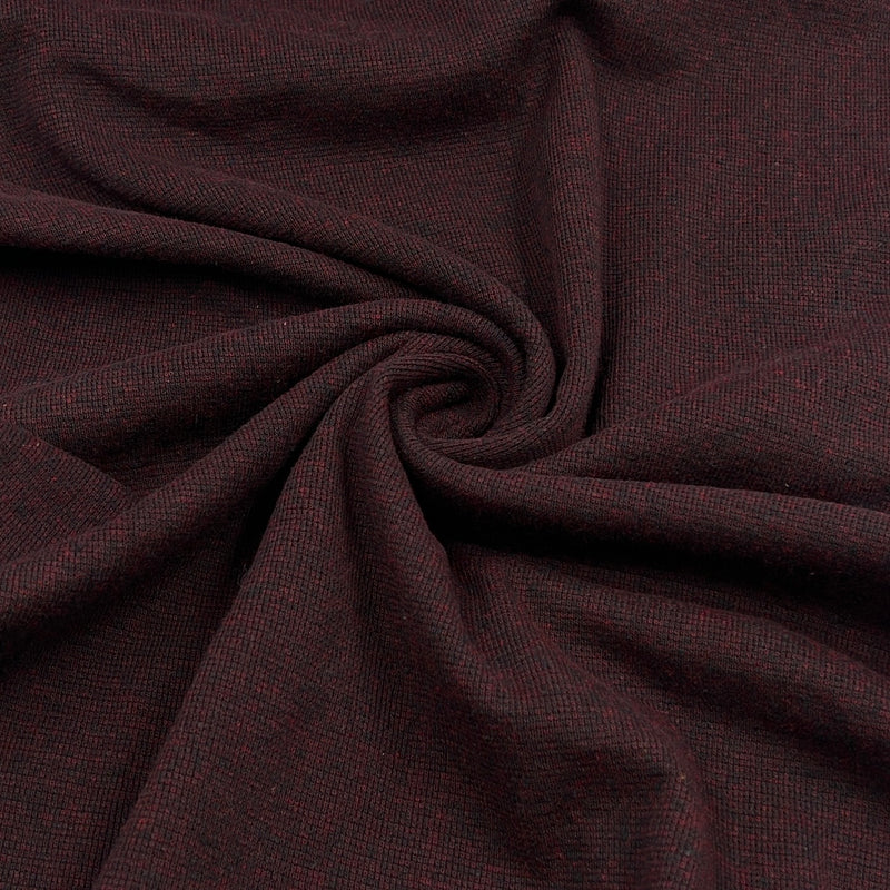 A close-up of dark burgundy fabric with a subtle woven texture, arranged in a spiral drape to show its softness and color.