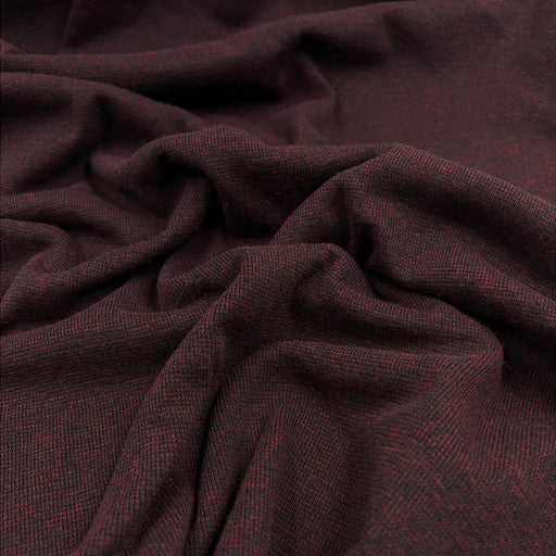 A close-up of draped fabric with a fine woven texture in a very dark burgundy-brown color, showing folds and the material's subtle heathering.