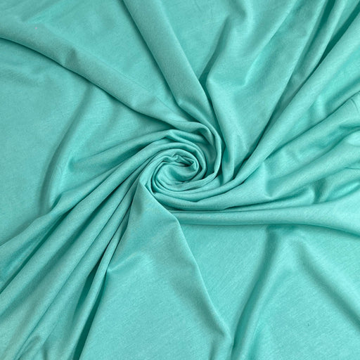 A close-up of mint green or aqua fabric arranged in a spiral drape, showing the material texture and color.