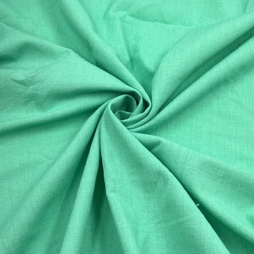 A close-up of mint green fabric arranged in a spiral drape, showing the material texture and color.