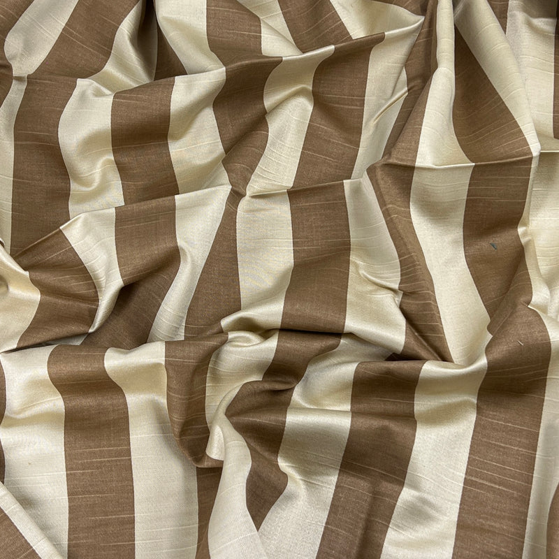 A close-up of draped fabric with alternating wide vertical stripes in warm taupe-brown and cream, showing a subtle woven texture.