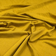 A close-up of draped mustard yellow fabric with a fine textured weave, showing soft folds and shadows.
