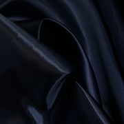 A close-up of draped dark navy satin fabric with soft folds and a subtle sheen.