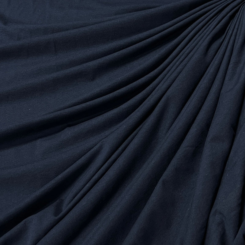A close-up of dark navy blue fabric with elegant drapes and folds.