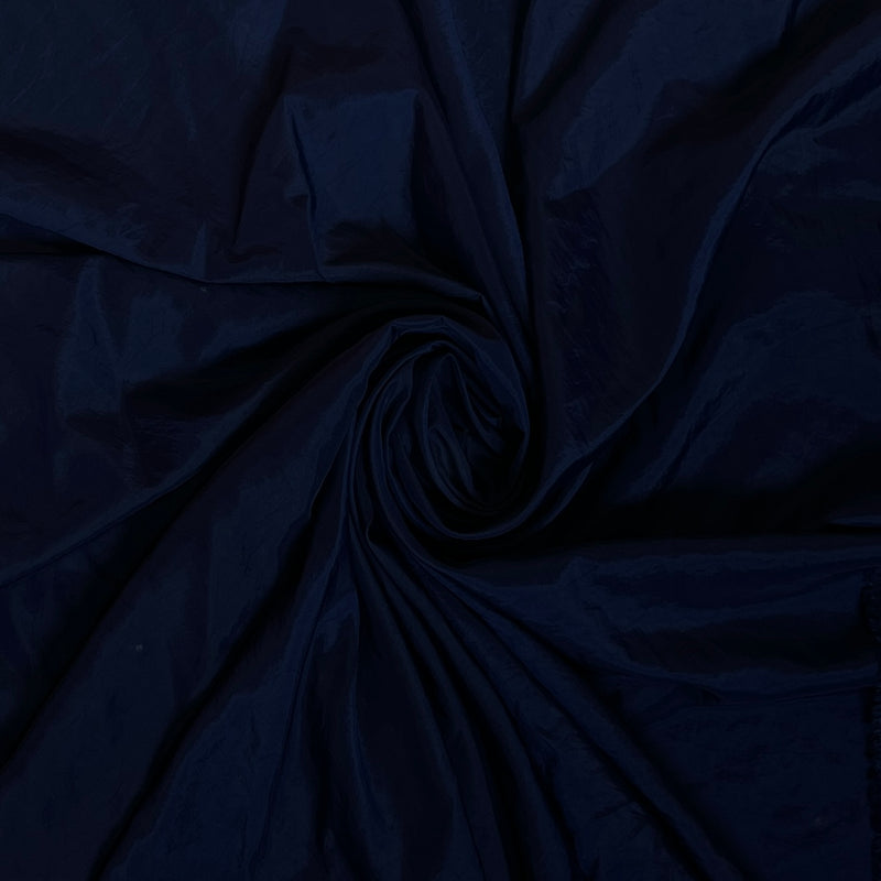 Dark navy blue fabric draped in a spiral swirl pattern, showing a smooth texture and subtle sheen.