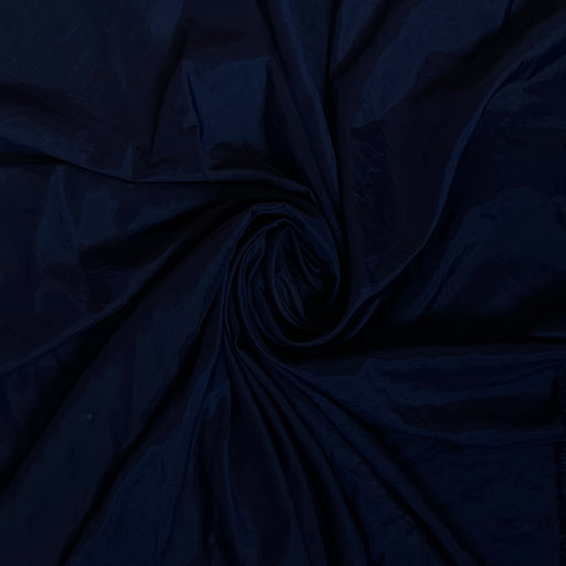 Dark navy blue fabric draped in a spiral swirl pattern, showing a smooth texture and subtle sheen.