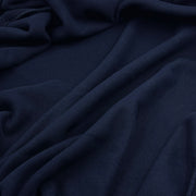 A close-up of draped navy blue fabric with soft folds and a smooth texture.