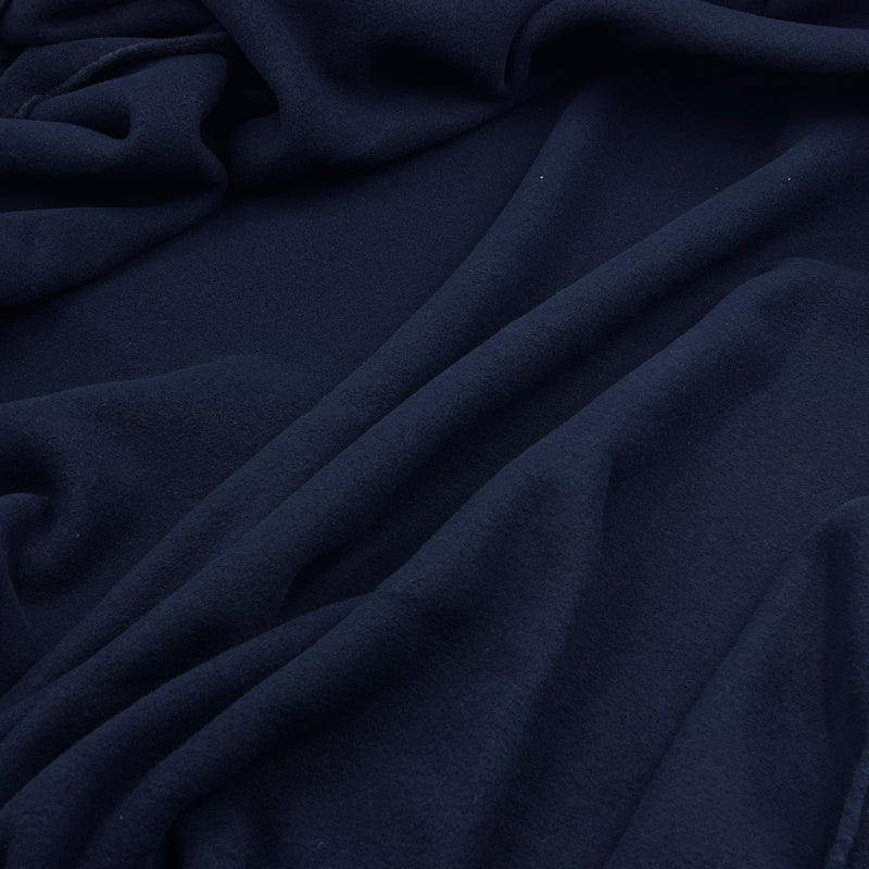 A close-up of draped navy blue fabric with soft folds and a smooth texture.