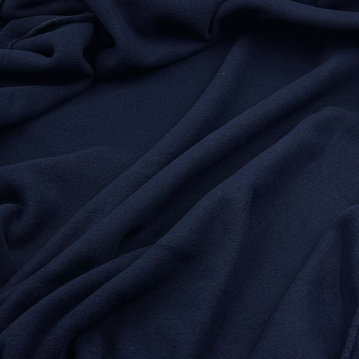 A close-up of draped navy blue fabric with soft folds and a smooth texture.
