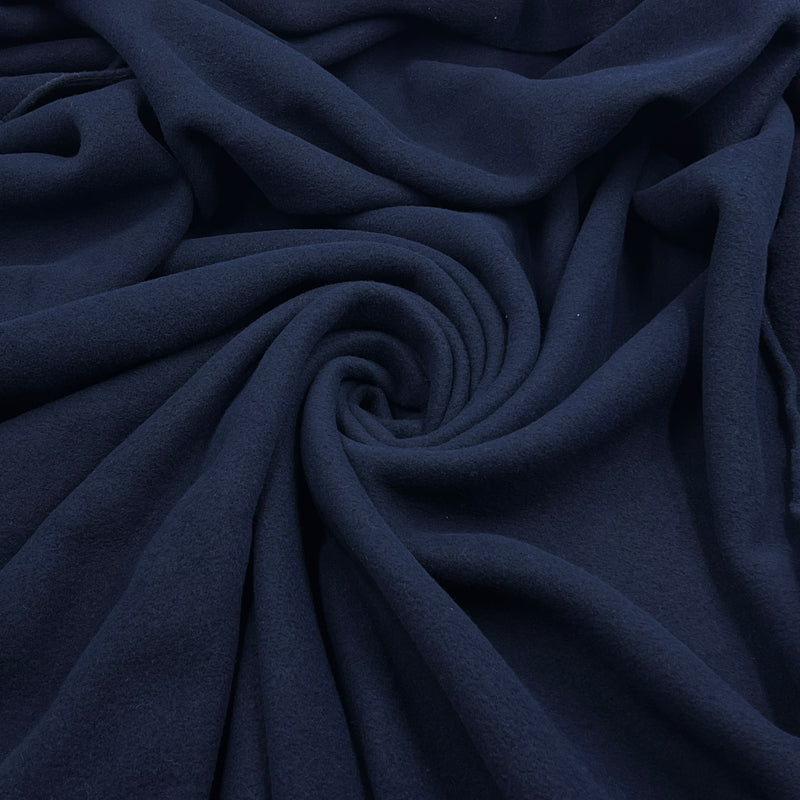A close-up of draped navy blue fabric arranged in a spiral pattern, showing its soft texture and folds.