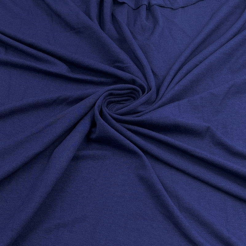 A close-up of dark blue fabric arranged in a spiral drape, showing the material texture and color.