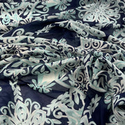 A close-up of draped fabric with an allover floral and scroll pattern in navy blue, pale mint green, and white.