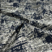 A close-up of draped fabric with an abstract, high-contrast pattern in black, gray, and white.