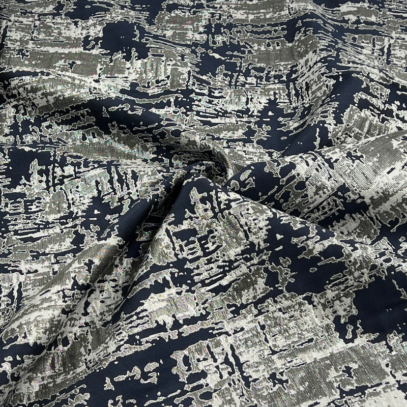 A close-up of draped fabric with an abstract, high-contrast pattern in black, gray, and white.