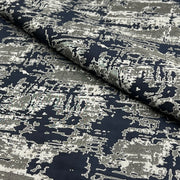 A close-up of a draped fabric with an abstract, distressed pattern in navy blue and off-white.