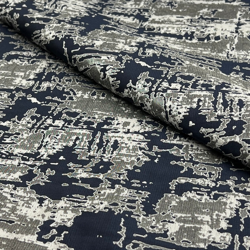 A close-up of a draped fabric with an abstract, distressed pattern in navy blue and off-white.